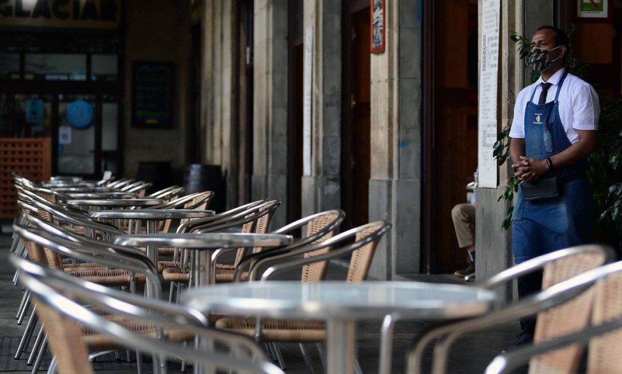 Um garçom espera por clientes em um restaurante em Barcelona, antes da entrada em vigor de novas medidas de restrição para reduzir o aumento das infecções por coronavírus Foto: LLUIS GENE / AFP