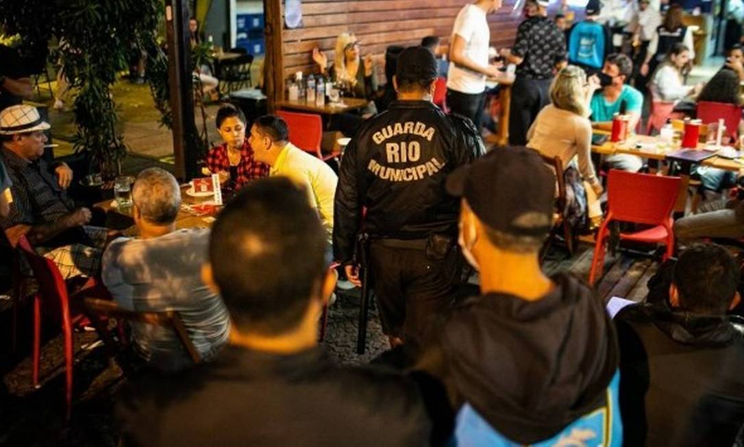 Guarda municipal circula entre mesas de bar onde as pessoas estão sem máscara Foto: Hermes de Paula/17-7-2020