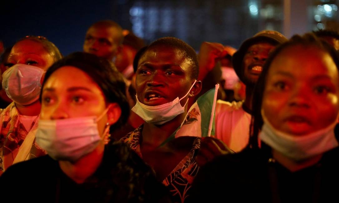 Um manifestante grita o slogan enquanto segura a bandeira nigeriana durante um protesto contra a suposta brutalidade policial em Lagos Foto: TEMILADE ADELAJA / REUTERS