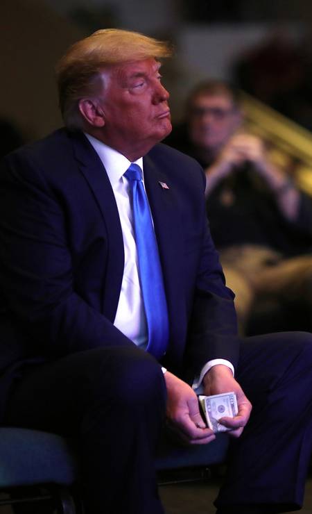 Trump holds up cash bills before donating them to the church during a service in Las Vegas Photo: CARLOS BARRIA / REUTERS