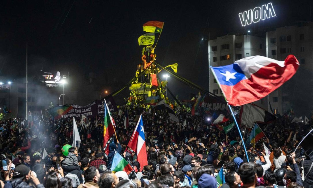 Chilenos comemoram, na noite de domingo, na Plaza Italia, na capital Santiago, a vitória esmagadora do referendo que decidiu a favor da substituição da Constituição promulgada na ditadura de Pinochet Foto: PEDRO UGARTE / AFP