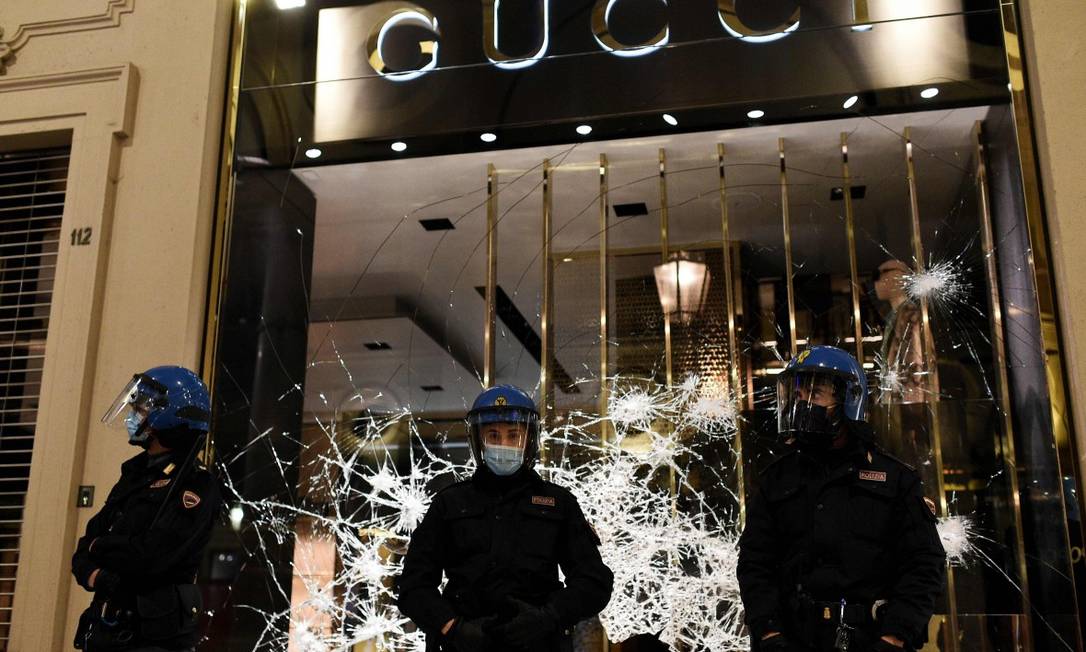 Policiais protegem loja da Gucci em Turim, destruída por manifestantes de extrema direita e torcidas organizadas Foto: MARCO BERTORELLO / AFP / 26-10-2020