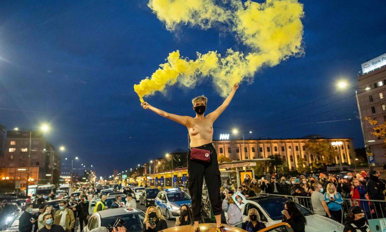 Uma mulher de peito nu balança sinalizador de cor amarela durante protesto, na noite de segunda-feira, que bloqueou o tráfego no centro de Varsóvia, contra uma decisão do Tribunal Constitucional sobre a restrição da lei de aborto Foto: WOJTEK RADWANSKI / AFP - 26/10/2020