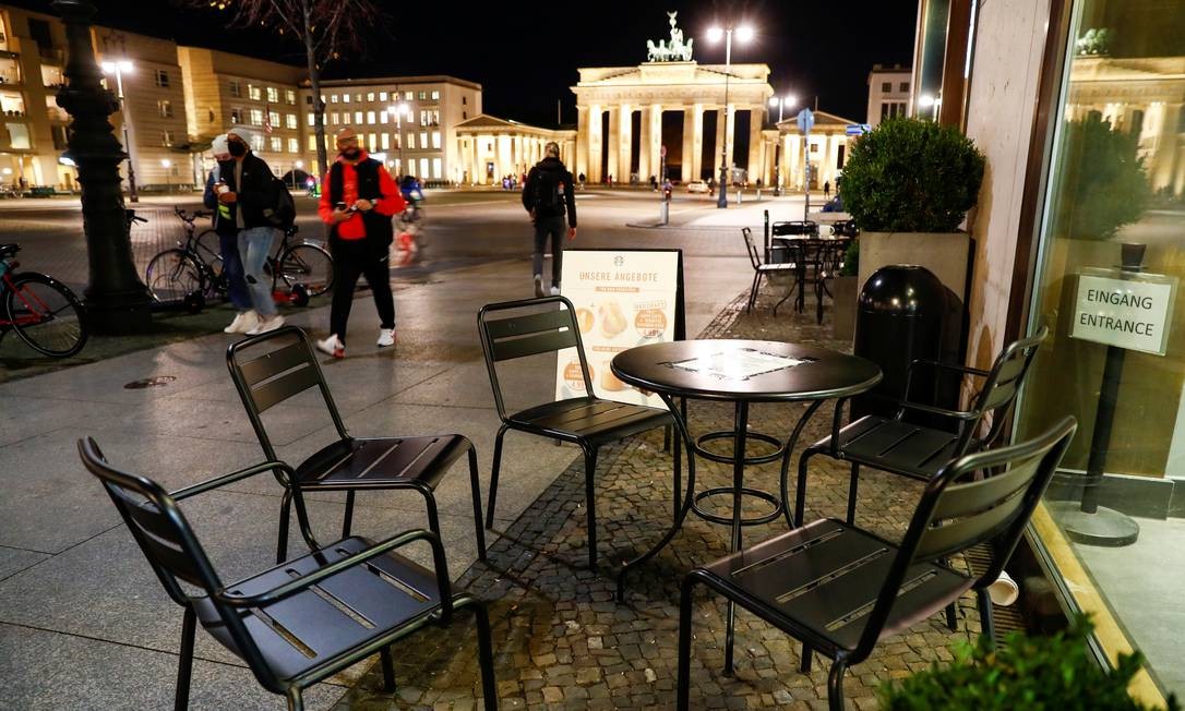 Pedestres passam por mesas vazias de um café em frente ao Portão de Brandemburgo, em Berlim, Alemanha. Governo do país decidiu nesta quarta-feira (28) decretar uma quarentena parcial a partir de 2 de novembro Foto: FABRIZIO BENSCH / REUTERS