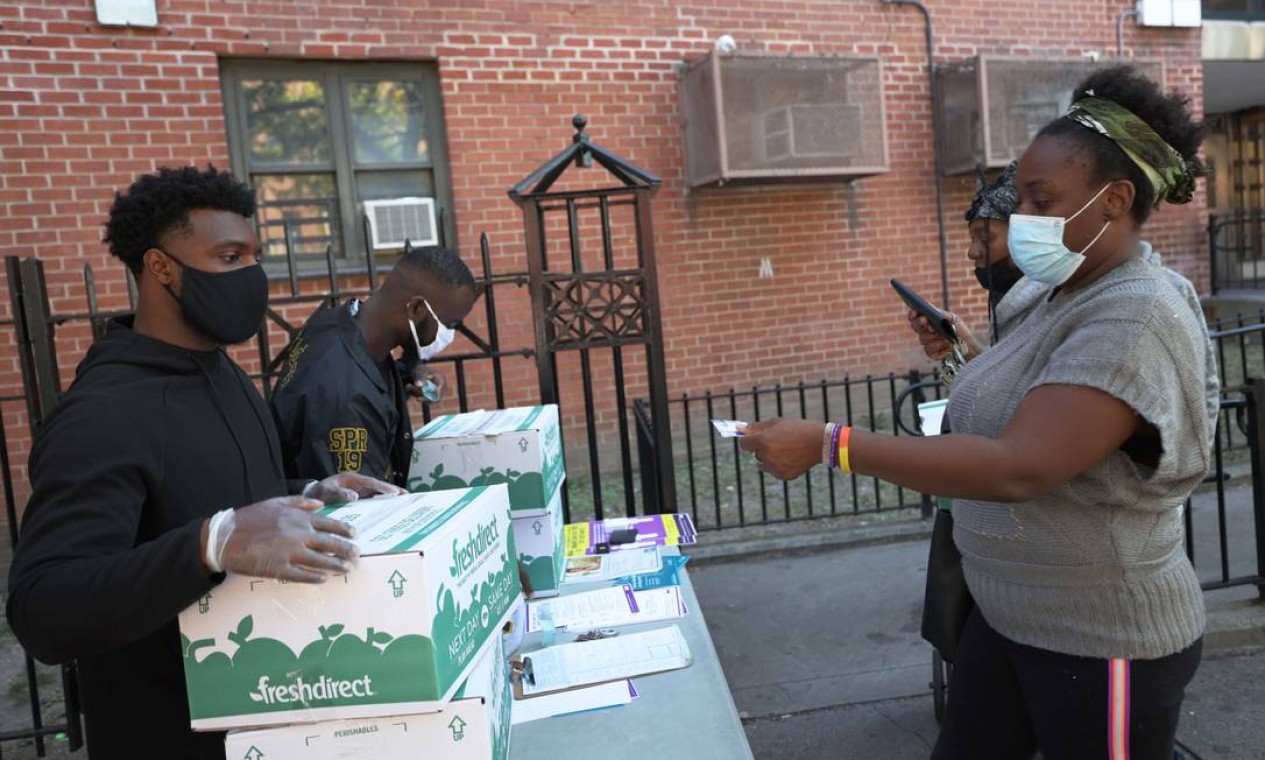 Moradores pegam caixas em centro de distribuição de comida em Nova York Foto: Michael M. Santiago / AFP
