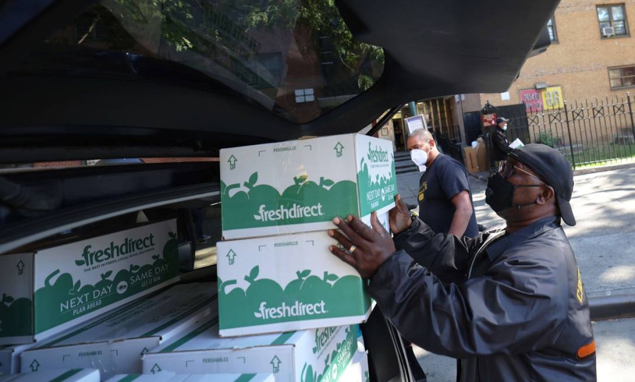 Gunthar Stroman embala um carro com caixas de comida FreshDirect para entregas durante uma entrega de comida no Harlem, na cidade de Nova York Foto: Michael M. Santiago / AFP