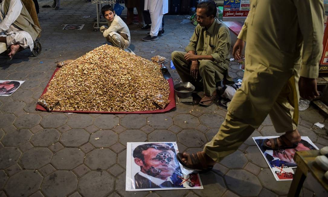 A pedestrian passes over posters with the photo of French President Emmanuel Macron pasted on a street in Pexauar, Pakistan.  Stepping, for Arabs, is one of the most offensive gestures possible.  The sole of the shoe is said to be dirty Photo: ABDUL MAJEED / AFP