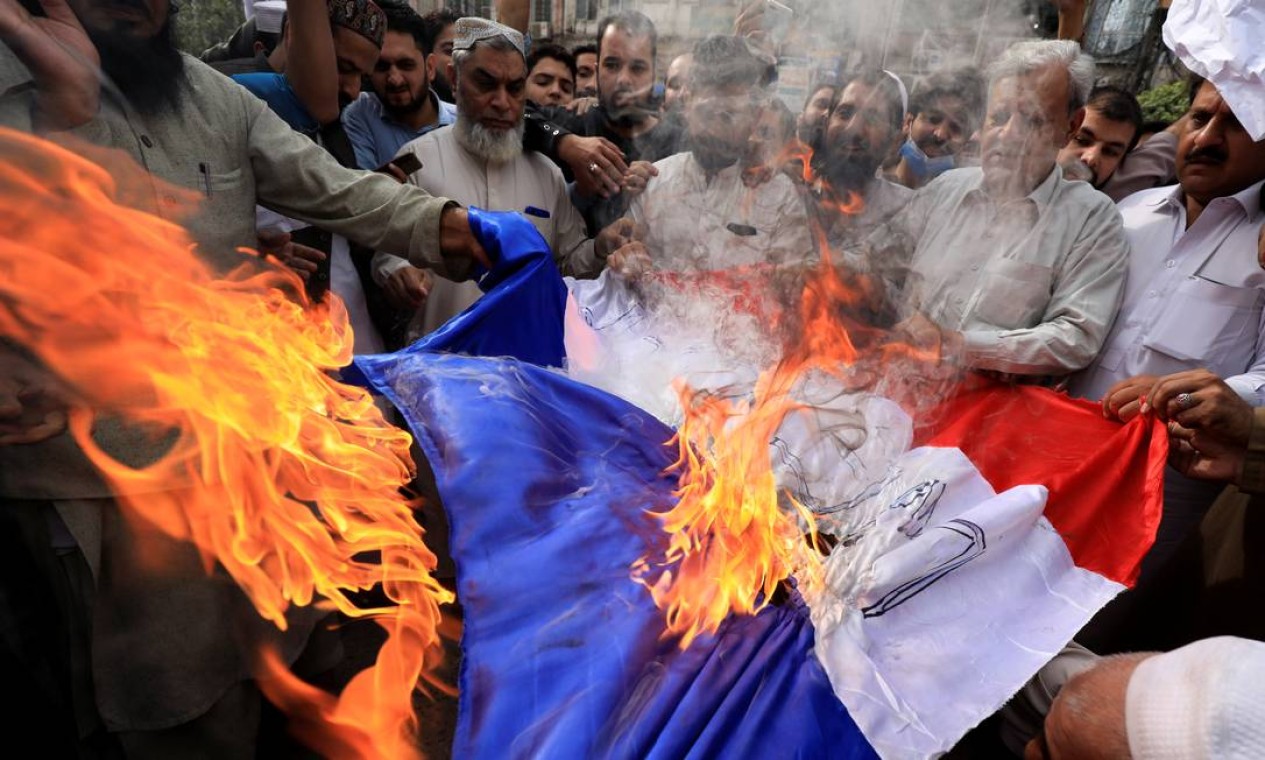 Em nome da fé - Pessoas queimam uma bandeira da França durante um protesto contra as publicações da revista Charlie Hebdo e declarações de Macron defendendo liberdade de expressão sobre a publicação de charges ridicularizando o profeta Maomé, em Peshawar, Paquistão Foto: FAYAZ AZIZ / REUTERS - 28/10/2020