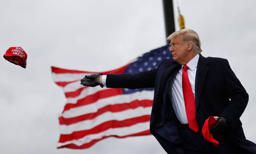 Trump joga bonés de "Faça os EUA grandes de novo" ao chegar para um comício de campanha no Michigan Foto: CARLOS BARRIA / REUTERS/30-102-2020