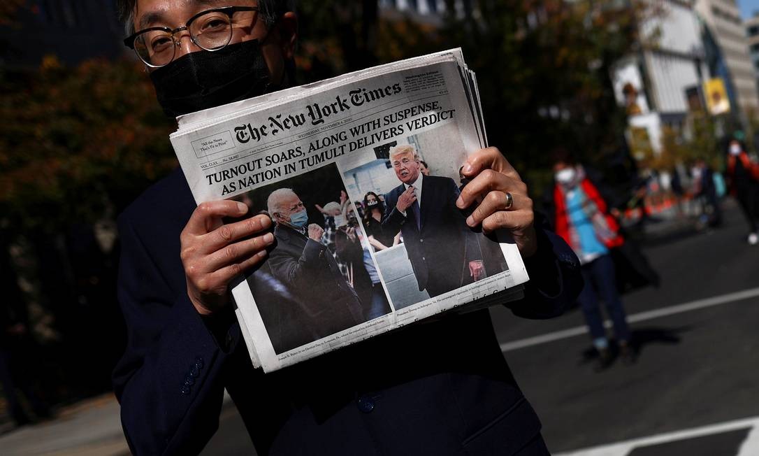 Um homem segura a edição do dia do jornal The New York Times, perto da Casa Branca, após o dia da eleição, em Washington Foto: HANNAH MCKAY / REUTERS
