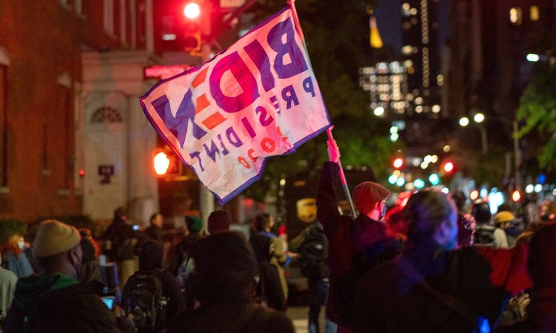 O manifestante agita a bandeira do candidato democrata Joe Biden na cidade de Nova York.  Foto: David Dee Delgado / AFP