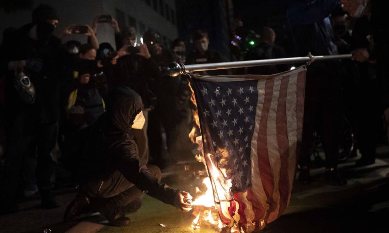Manifestantes do Black Bloc queimam uma bandeira dos EUA em Portland, Oregon Foto: Nathan Howard / AFP