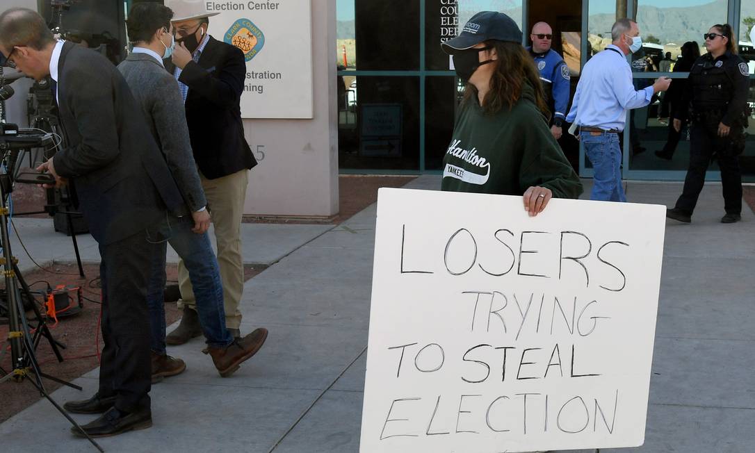 Manifestante do lado de fora de local de votação em Las Vegas, com cartaz dizendo "perdedores tentando roubar a eleição" Foto: Ethan Miller / AFP