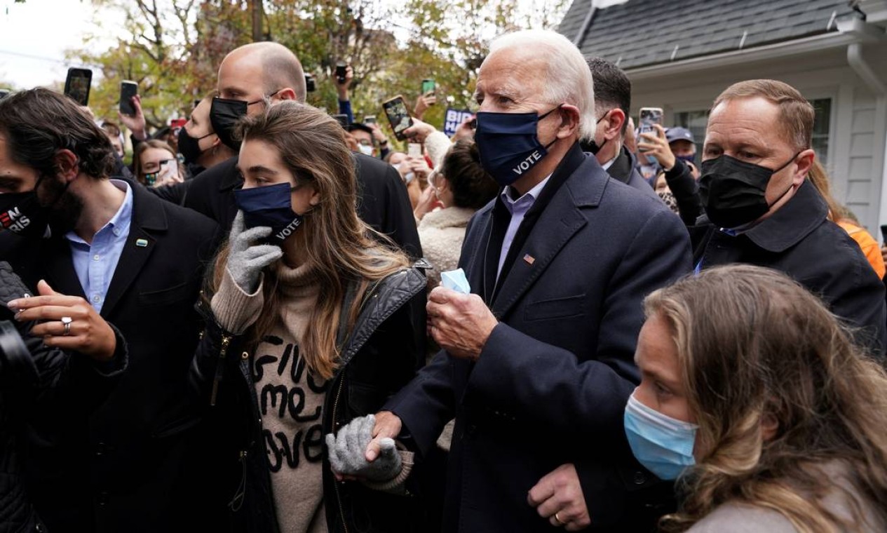 Joe Biden abre caminho pela multidão fora de sua casa de infância, no dia da eleição, em Scranton, Pensilvânia. "Até o dia das eleições, a ameaça do coronavírus restringiu a campanha de Joe Biden, sem multidões e pouca interação com o público em geral. Aqui, em um tour retrospectivo de sua cidade natal, Scranton, Pensilvânia, Biden se mistura mais livremente com apoiadores reunidos em sua casa de infância, ladeado por suas netas que o ajudam no meio da multidão". Foto: KEVIN LAMARQUE / REUTERS