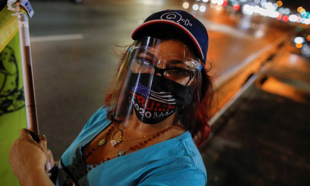 Uma apoiadora do presidente Trump observa durante um protesto em Miami, Flórida Foto: MARCO BELLO / REUTERS