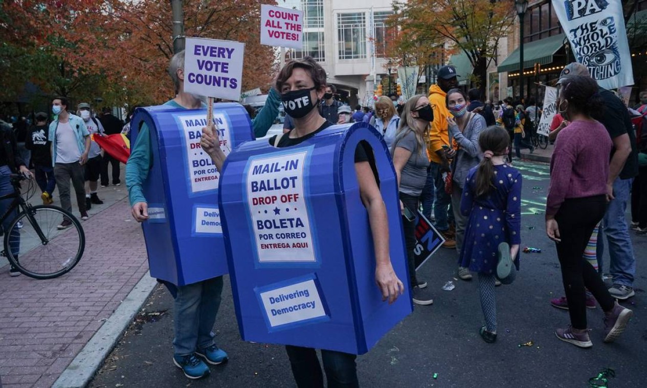 Manifestantes vestidos como caixas de correio dançam do lado de fora do Centro de Convenções na Filadélfia, Pensilvânia, enquanto a contagem de votos continua Foto: BRYAN R. SMITH / AFP