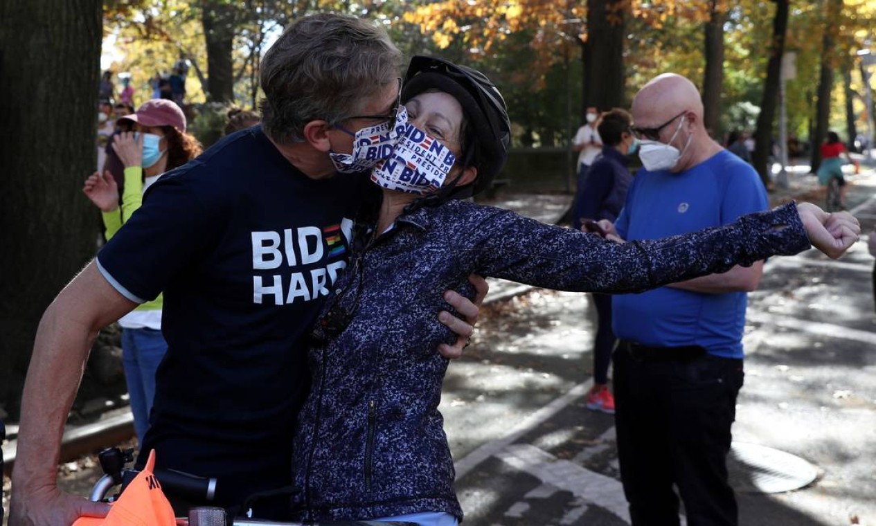 Casal se beija, de máscara, no Central Park, em Nova York, enquanto comemoram a vitória de Joe Biden Foto: CAITLIN OCHS / REUTERS
