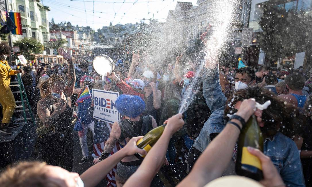 Eleitores estouram champanhe na comemoração da eleição de Biden, no distrito de Castro, em San Francisco, Califórnia. Foto: JOSH EDELSON / AFP