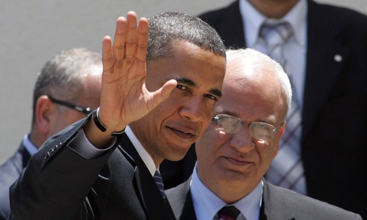 Obama, em 2008, então senador dos Estados Unidos e candidato à presidência, acena para a imprensa ao ser recebido pelo negociador palestino Saeb Erakat na cidade de Ramallah Foto: ABBAS MOMANI / AFP