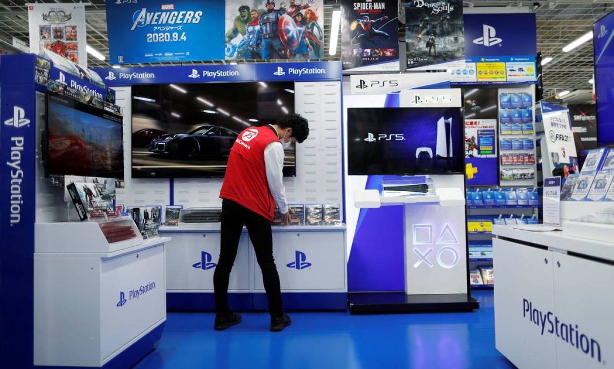 Um funcionário organiza uma prateleira de exibição de jogos do PS5 antes do lançamento oficial do console em Tóquio, Japão. As duas fabricantes disputarão a preferência do público durante a temporada de Natal, tradicionalmente lucrativa para a indústria de games Foto: ISSEI KATO / REUTERS