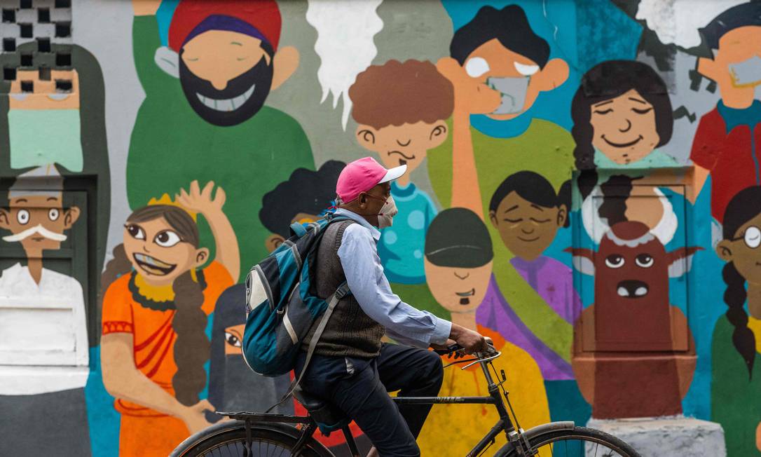 Homem usando uma máscara facial como medida preventiva contra o coronavírus anda de bicicleta por uma rua na Índia Foto: Jewel Samad / AFP