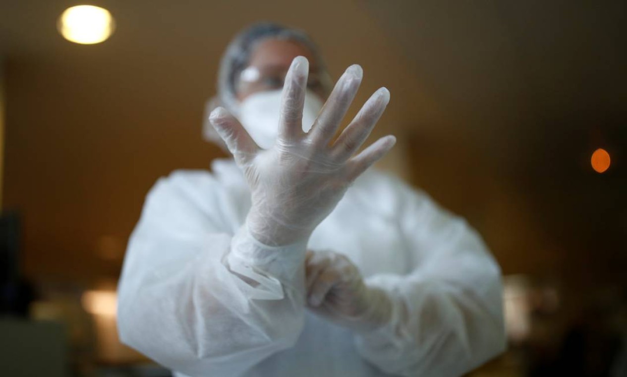 Médico vestindo traje de proteção ajusta sua luva antes de atender um paciente em UTI de hospital em Vannes Foto: STEPHANE MAHE / REUTERS