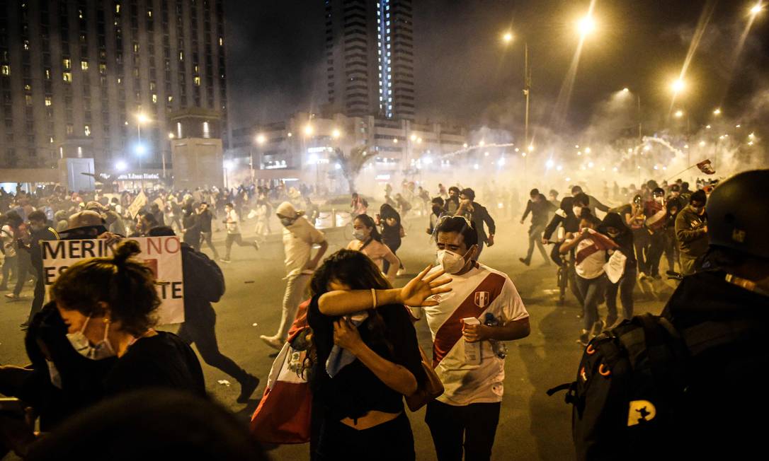 Manifestantes se protegem contra gás lacrimogêneo lançado pela polícia em Lima: confrontos em protestos deixaram dezenas de feridos Foto: ERNESTO BENAVIDES / AFP