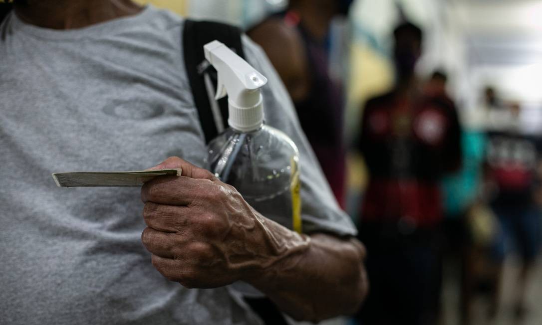 Título de eleitor e álcool em gel em mãos na hora de votar Foto: Hermes de Paula / Agência O Globo