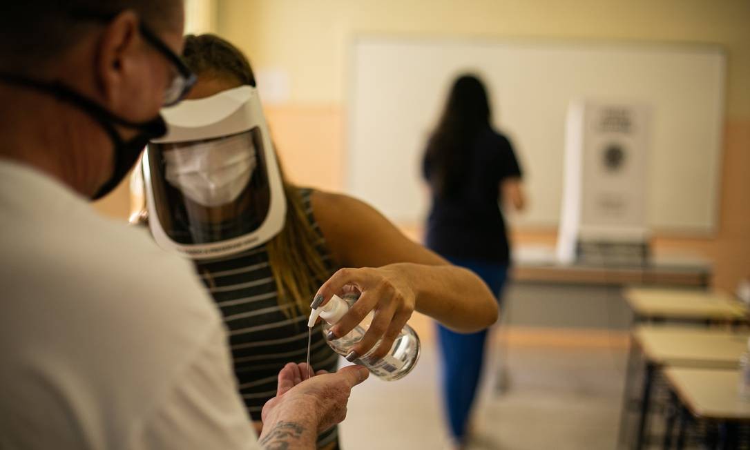 Eleitor tem as mãos higienizadas entes de entrar em seção eleitoral no Colégio Estadual Amaro Cavalcanti, no Largo do Machado Foto: Hermes de Paula / Agência O Globo
