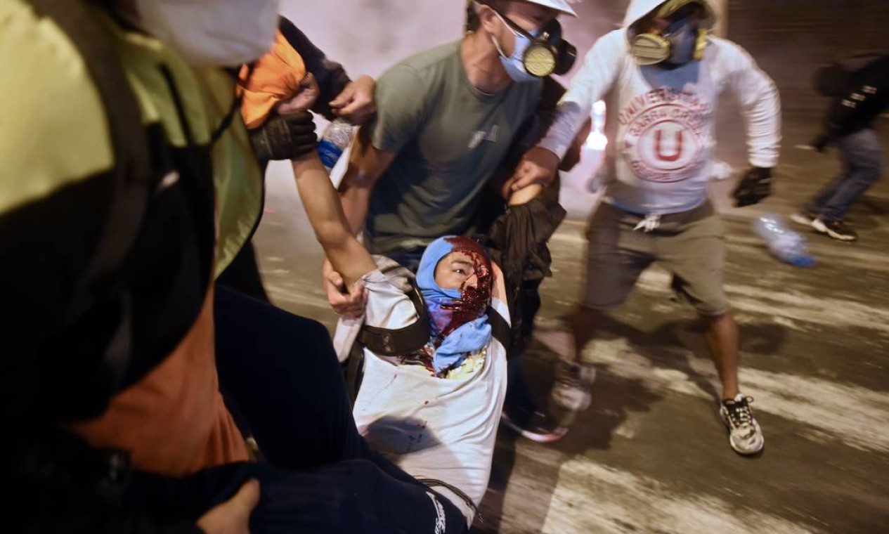 Manifestante peruano é carregado por colegas durante protesto Foto: ERNESTO BENAVIDES / AFP - 14/11/2020