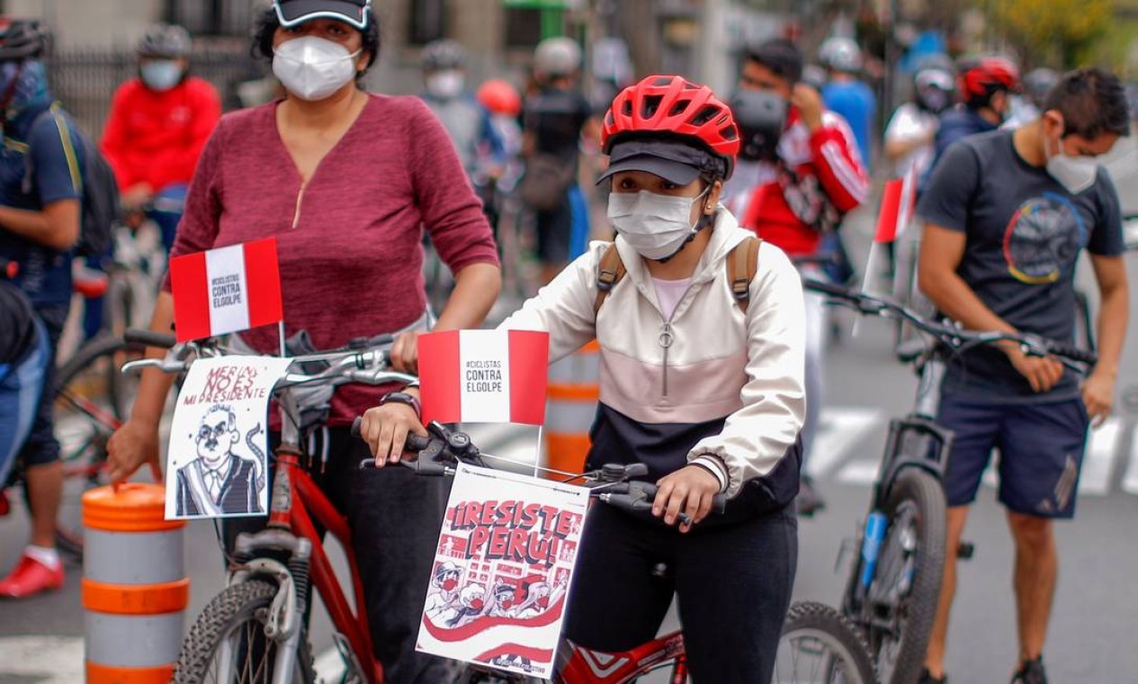 Manifestantes de bicicelta carregam cartazes contra o governo interino: "Merino não é meu presidente" e "Peru resiste", dizem os cartazes Foto: LUKA GONZALES / AFP - 15/11/2020