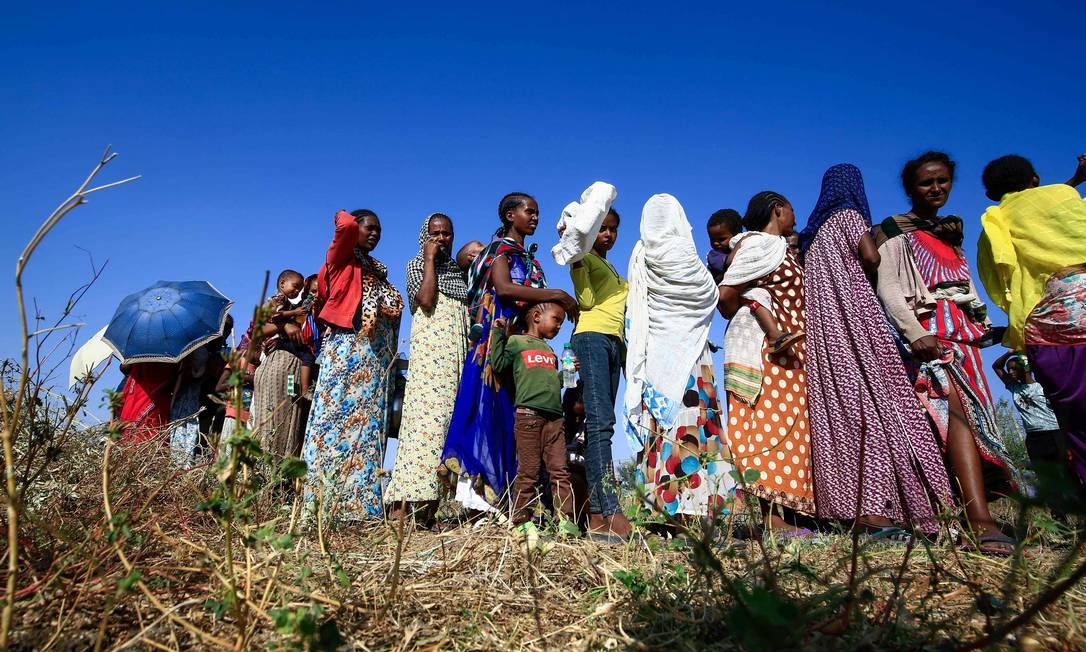 Etiopes que fugiram do conflito na região de Tigré aguardando comida no Sudão Foto: Ashraf Shazly / AFP