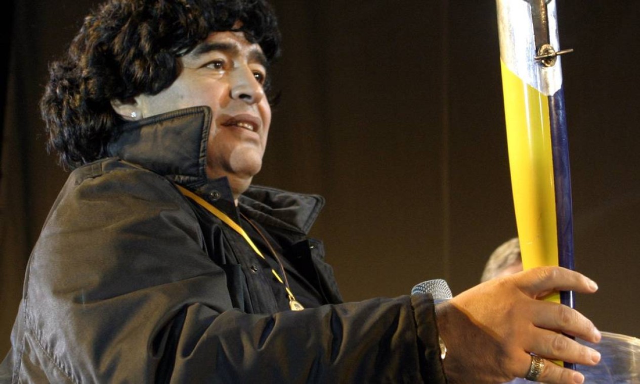Carregando a Tocha do Centenário, o ex-astro do futebol argentino Diego Maradona entra no estádio do Boca Juniors como parte das comemorações do 100º aniversário do clube em Buenos Aires Foto: Marcos Brindicci / Reuters - 03/04/2005