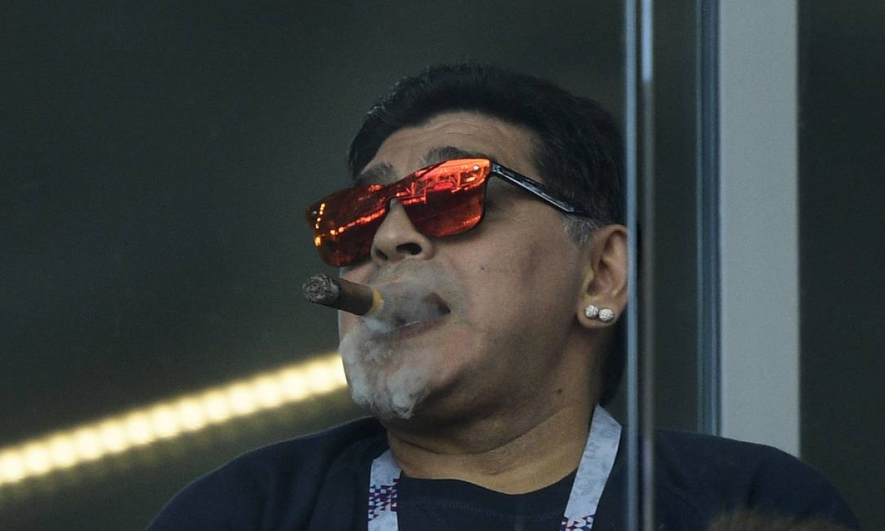 Diego Maradona fuma um charuto durante partida de futebol do Grupo D da Copa do Mundo da Rússia 2018 entre Argentina e Islândia, no Estádio Spartak, em Moscou Foto: JUAN MABROMATA / AFP