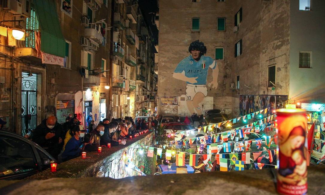Pessoas se reúnem no topo do Quartieri Spagnoli em Nápoles em 25 de novembro de 2020 por um mural de 1990 representando a lenda do futebol argentino Diego Maradona, após o anúncio da morte de Maradona Foto: CARLO HERMANN / AFP