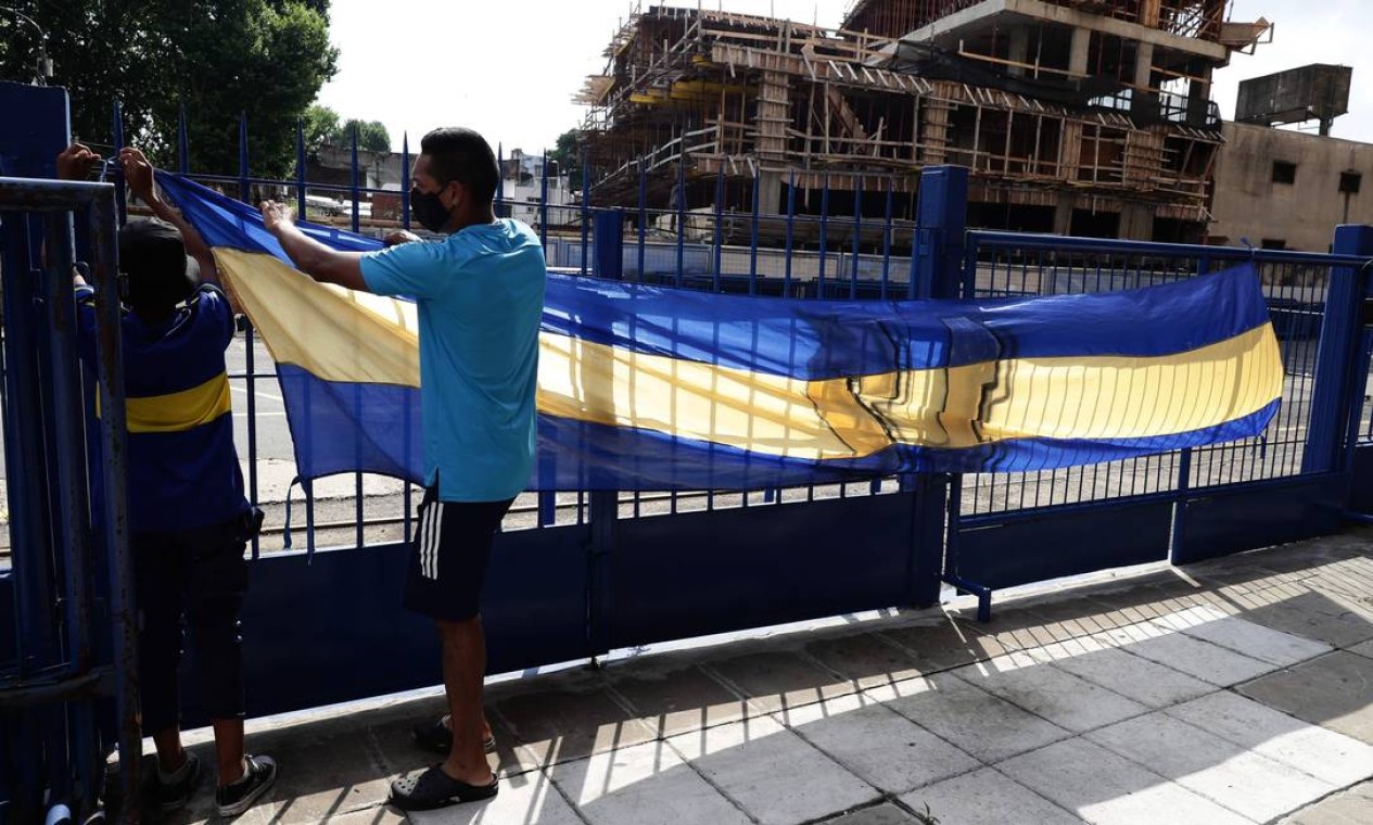 Torcedores do Boca Juniors penduram a bandeira próxiomo ao estádio La Bombonera, onde as pessoas se reúnem para lamentar a morte do astro do futebol argentino Diego Maradona em Buenos Aires Foto: ALEJANDRO PAGNI / AFP
