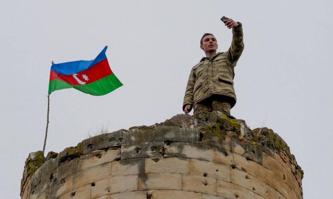 Soldado azerbaijano tira selfie em uma torre na cidade de Fuzuli, que segundo o acordo voltou ao controle do país; para analistas, Moscou quis evitar avanço ainda maior dos turcos, que apoiaram Baku Foto: TOFIK BABAYEV / AFP/9-11-2020