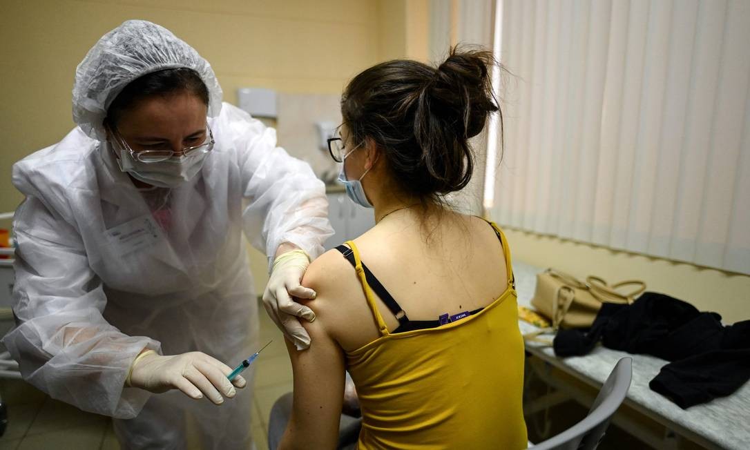No primeiro dia de vacinação contra coronavírus na Rússia, enfermeira aplica a Sputnik V em uma mulher em Moscou Foto: KIRILL KUDRYAVTSEV / AFP