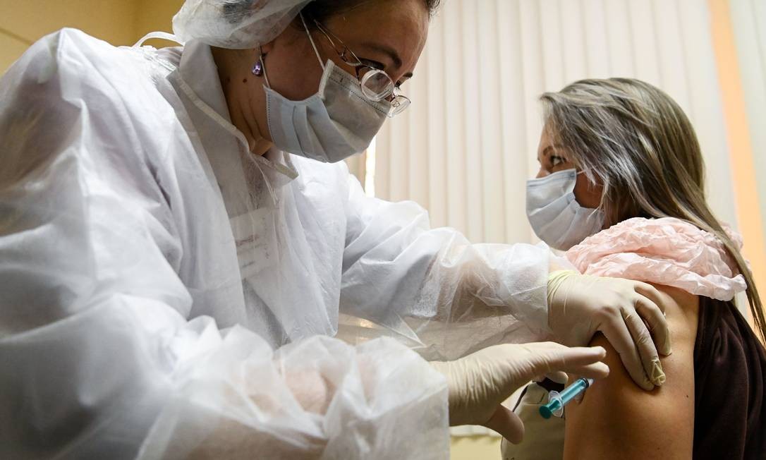 Enfermeira aplica uma dose da Sputnik V em uma mulher no primeiro dia de vacinação contra o coronavírus, em uma clínica em Moscou Foto: KIRILL KUDRYAVTSEV / AFP