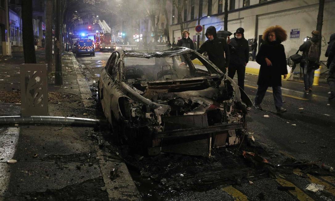 People walk through the remains of a burning car during a demonstration in Paris Photo: GEOFFROY VAN DER HASSELT / AFP