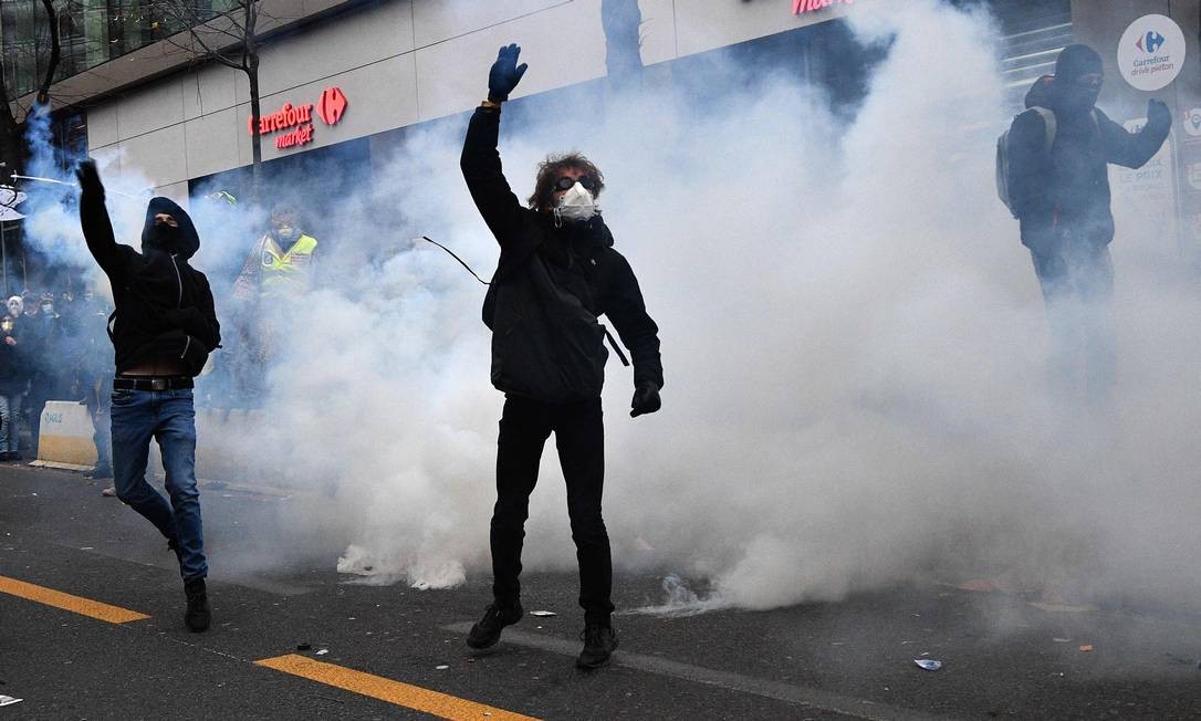 Demonstrators, surrounded by tear gas smoke, throw gas canisters during the confrontation with police officers Photo: ANNE-CHRISTINE POUJOULAT / AFP