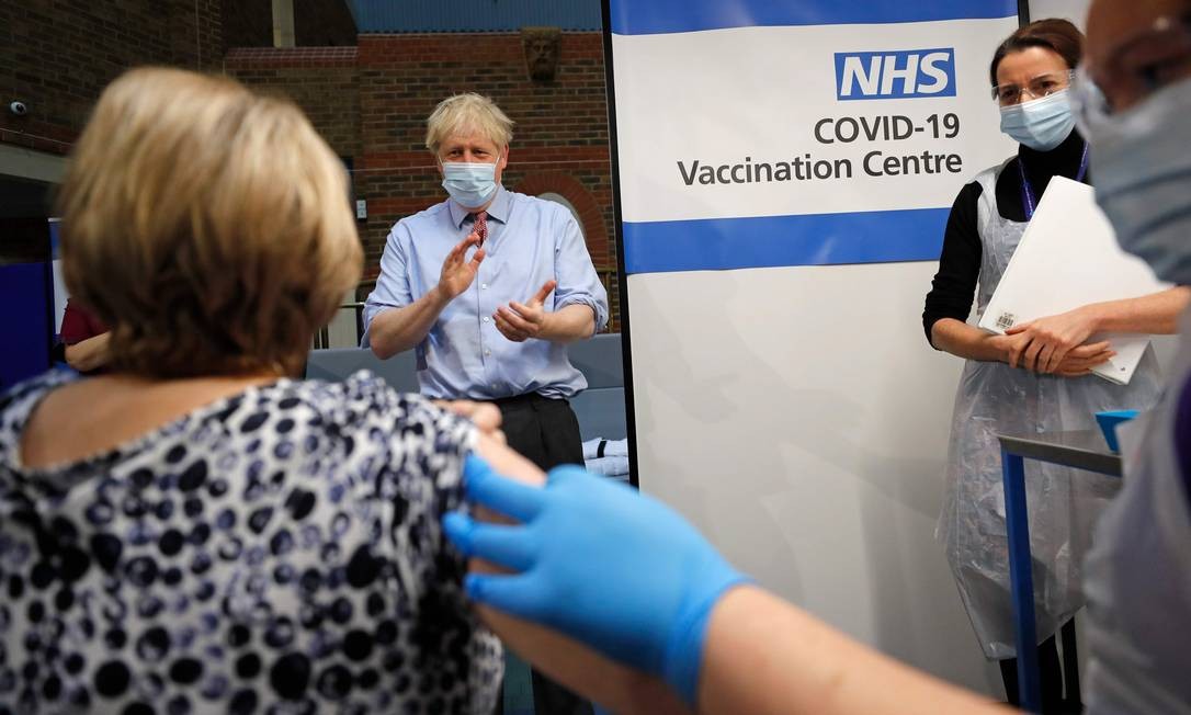 O primeiro-ministro da Grã-Bretanha, Boris Johnson, aplaude depois que a enfermeira Rebecca Cathersides administrou a vacina da Pfizer, laboratório dos EUA, desenvolvida em parceria com o alemão BioNTech, em Lyn Wheeler no Guy's Hospital em Londres Foto: FRANK AUGSTEIN / AFP