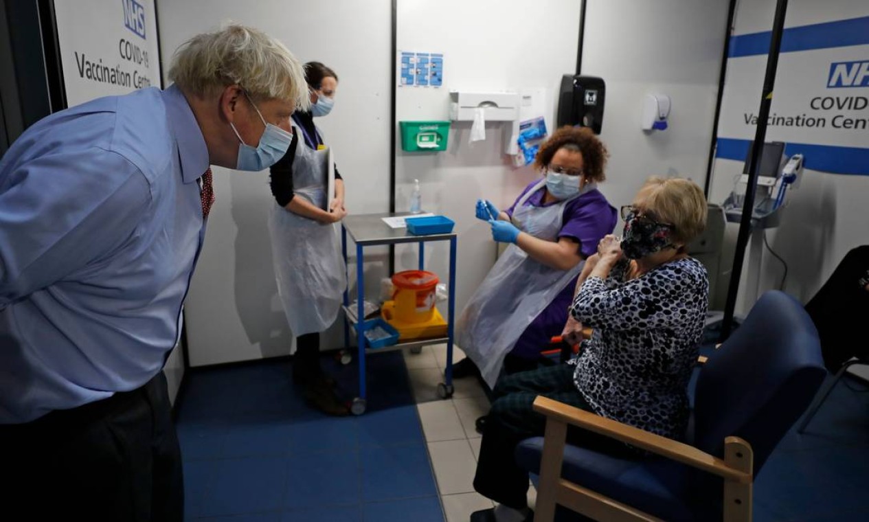 O primeiro-ministro da Grã-Bretanha, Boris Johnson, fala com Lyn Wheeler antes que a enfermeira Rebecca Cathersides administre a vacina contra Covid-19 no Guy's Hospital em Londres Foto: FRANK AUGSTEIN / AFP