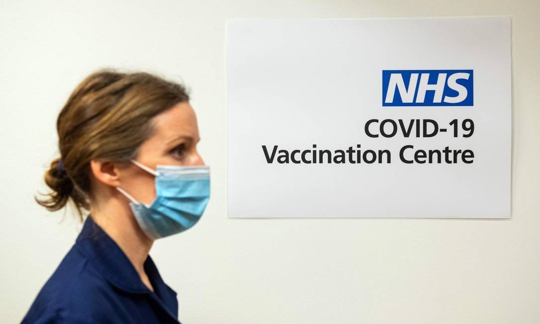 Enfermeira passa por uma placa indicando um Centro de Vacinação Covid-19 no Royal Free Hospital, em Londres Foto: DOMINIC LIPINSKI / AFP