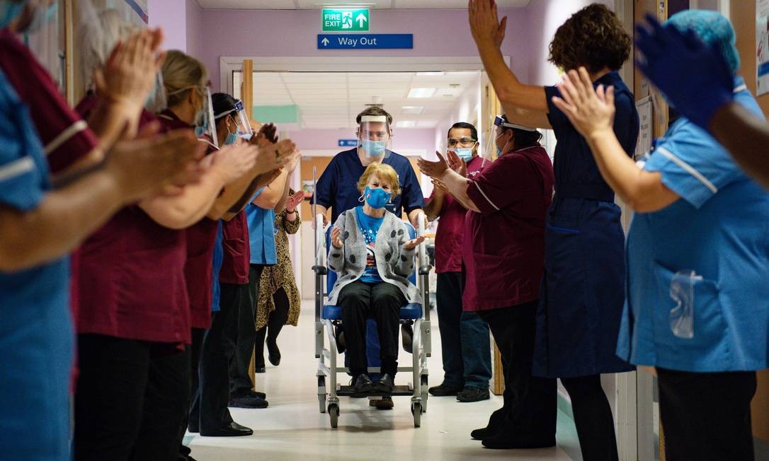 Margaret Keenan, 90 anos, é aplaudida pela equipe ao retornar para sua enfermaria depois de se tornar a primeira pessoa a receber a vacina contra Covid-19, no Hospital Universitário em Coventry, região central da Inglaterra Foto: JACOB KING / AFP