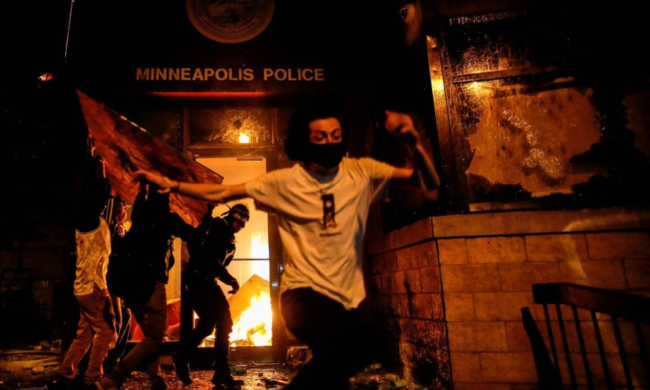 Os manifestantes correm ao atearem fogo na entrada de uma delegacia de polícia depois da divulgação do vídeo em que um policial branco aparece pressionando seu joelho sobre o pescoço de George Floyd, que morreu sufocado pela ação, em Minneapolis, Minnesota Foto: CARLOS BARRIA / REUTERS - 28/05/2020