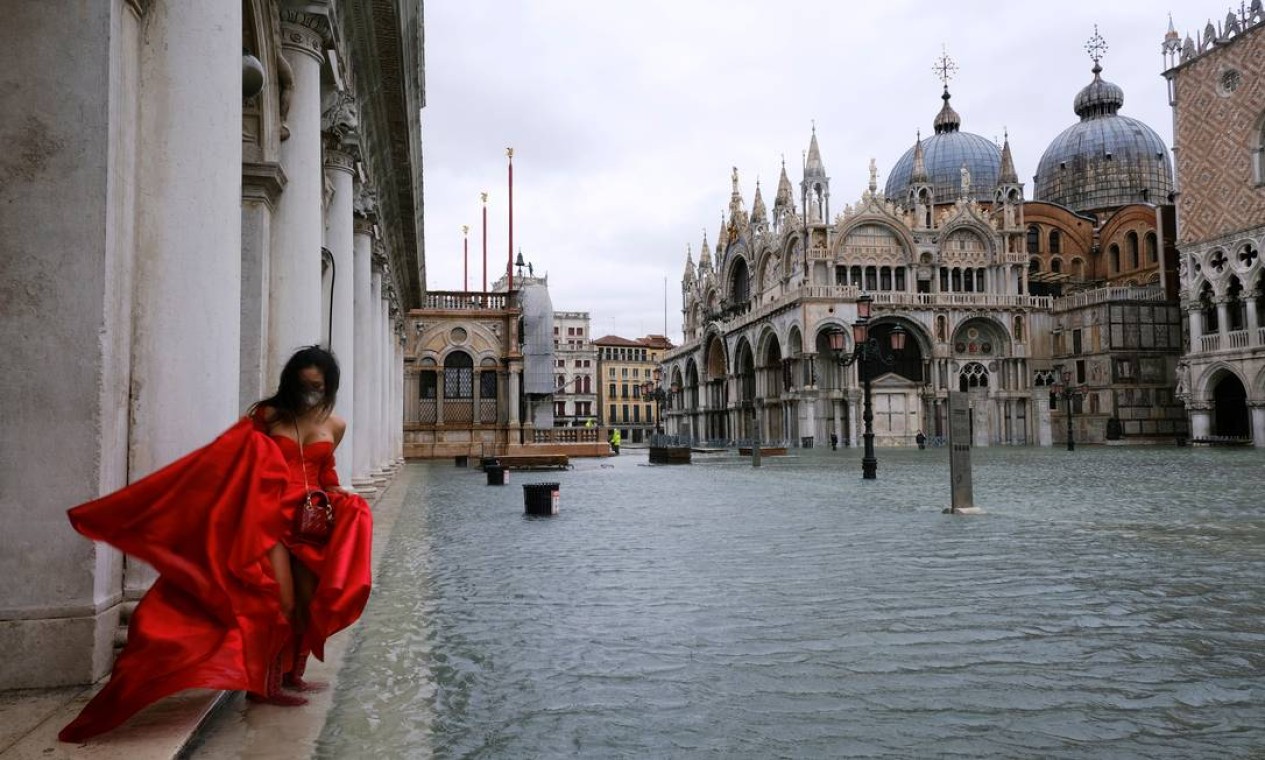 Mulher está parada na inundada Praça de São Marcos durante a maré alta enquanto as barreiras contra enchentes conhecidas como Mose não são levantadas, em Veneza, Itália Foto: MANUEL SILVESTRI / REUTERS