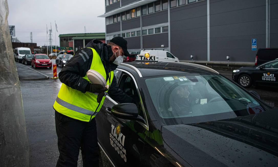 Taxista em Estocolmo, na Suécia, retira kits de teste de Covid-19 em um ponto de coleta para levar a pessoas com sintomas da doença Foto: JONATHAN NACKSTRAND / AFP