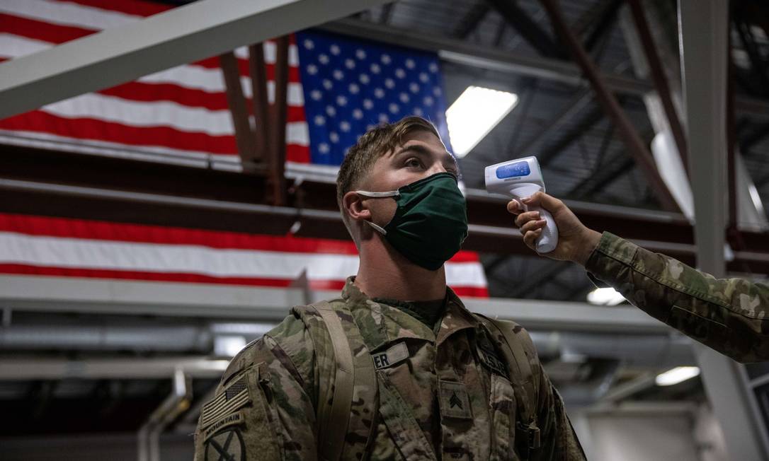 De máscara, soldado americano tem sua temperatura conferida no Forte Drum, em Nova York, ao retornar do Afeganistão Foto: JOHN MOORE / AFP / 8-12-2020
