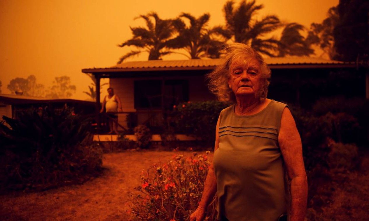 Janeiro - Nancy Allen posa em frente à casa sob o céu alaranjado, devido ao incêndio de Currowan em direção a Nowra, Nova Gales do Sul. Incêndios florestais saíram de controle na Austrália entre 2019 e 2020 Foto: TRACEY NEARMY / REUTERS - 04/01/2020